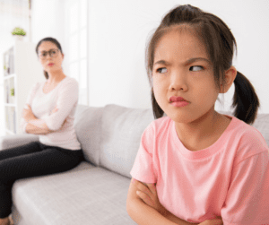 Young girl angry with adult sitting on a couch.