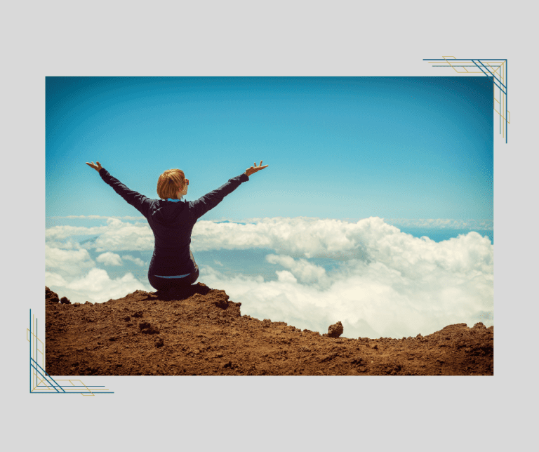 Woman sitting on a mountaintop with her arms extended. Showing that she's ready to face her fear of divorce.
