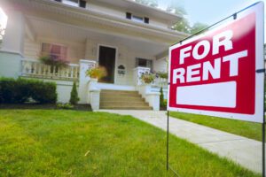 Pretty suburban home with rent sign in yard.