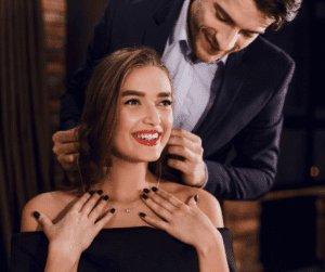 Man putting a necklace around a woman's neck.