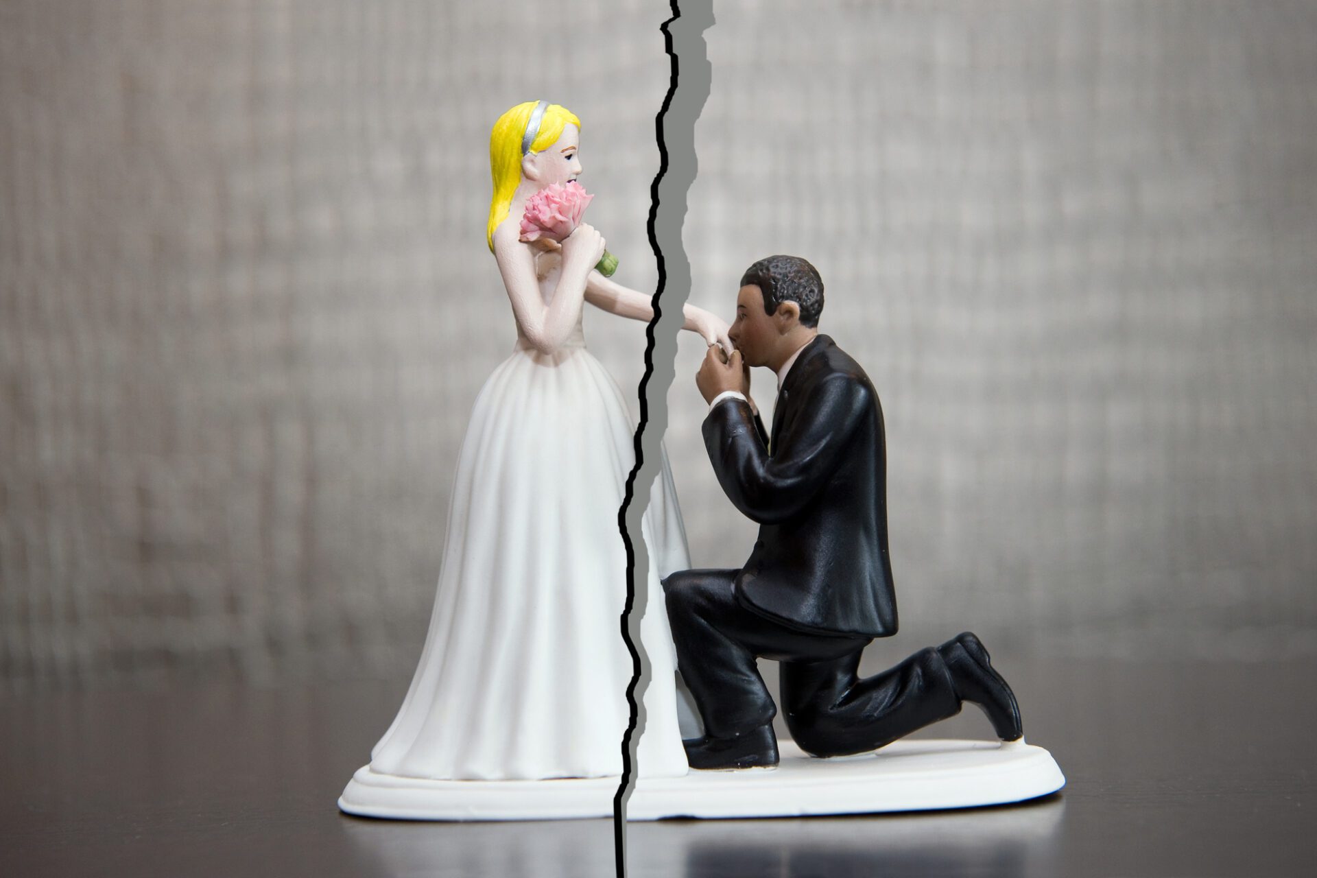 Wedding cake topper of bride and groom with slash through the image depicting divorce or annulment.
