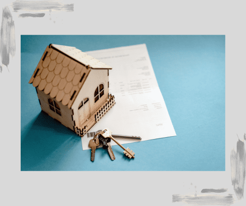 Toy house sitting on a piece of complex paperwork with a set of keys in front of it on a medium blue background. 