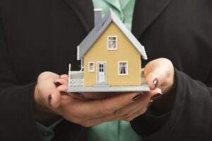 Woman holding a model of a house in her hands.